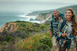 © SnapVault - A middle-aged couple, energetically hiking on a verdant coastal path, enjoys the refreshing ocean breeze and vibrant orange wildflowers.