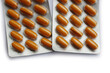 Pharmaceutical medicine capsules isolated on white background. Orange pills in blister packaging