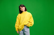 © Lustre Art Group  - Portrait of young brunette woman with short hair posing in yellow sweatshirt and looking at camera against vibrant green studio background. Concept of human emotions, fashion, beauty, style.