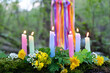 colorful magic candles and flowers in forest, natural background. Witch ritual for Beltane or Litha sabbat. Midsummer. Witchcraft, esoteric spiritual practice, divination. mysterious fairy scene