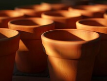 3D Render Of A Row Of Terracotta Pots Sit On A Table. The Pots Are All Different Sizes And Are Arranged In A Neat Row. The Sunlight Casts A Warm Glow On The Pots, Making Them Look Even More Inviting
