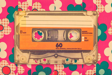 Wall Mural - vintage orange audio compact cassette in front of a background with flower pattern