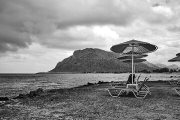 Wall Mural - Umbrellas on the rocky beach on a cloudy day in Stavros on the island of Crete