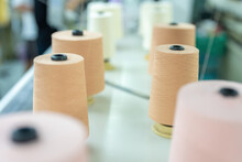 Rolls Of Multi-colored Thread Are Arranged In Rows, Several Rolls Of Material Used For The Production Of Clothes And Dresses Are Located On A Weaving Machine In The Sewing Industry.