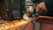 worker grinding a metal structure with sparks in a workshop