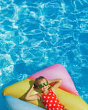 Fototapeta Lawenda - Cute happy girl wearing sunglasses in swimming resort pool - colorful vacation concept. Poster.