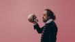 Modern photo of William Shakespeare holding a skull in his hand, isolated on trendy pastel background.