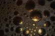 Burbujas de agua con jabón en una superficie texturada, con luz rasante ilumina sus bordes de color dorado, formando un original diseño abstracto para fondos de pantalla.