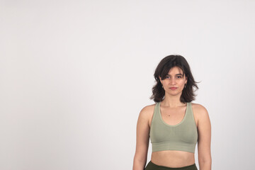 confident young woman in casual attire standing against a plain background with copy space.