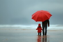 A Man And A Child Are Walking On A Beach Holding A Red Umbrella