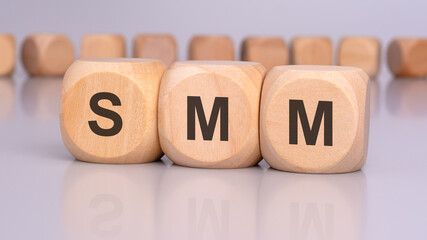 Sticker - image depicts three wooden blocks with the letters 'SMM' in focus, reflecting on the table surface