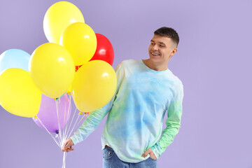 Sticker - Young man with bunch of colorful balloons on lilac background