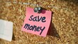 note pinned to a corkboard that says save money