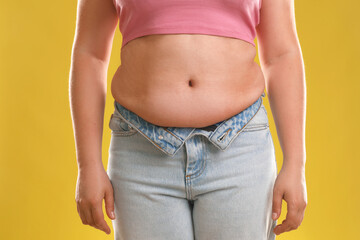 Sticker - Woman with excessive belly fat on goldenrod background, closeup. Overweight problem