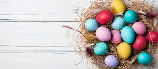 Wall Mural - A detailed view of a nest containing various colored eggs placed on a rustic white wooden table