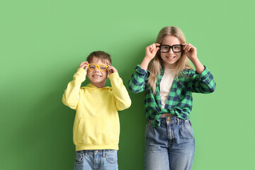 Wall Mural - Cute little children in eyeglasses on green background