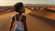 Bellissima donna di origini africane  sorride felice mentre cammina sulle dune di un deserto durante una vacanza