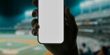 Fototapeta  - A hand holds a smartphone with a blank screen at a baseball stadium