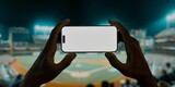 Fototapeta Sawanna - A hand holds a smartphone with a blank screen at a baseball stadium
