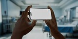 Fototapeta  - Black African-American male using smartphone with a blank screen in hospital