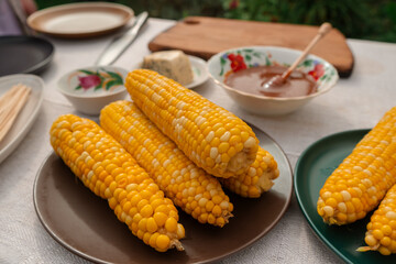 Hot boiled corn with bright yellow grains lies on table. Zea mays. Healthy food corncob from vegetables and cereals. Vegetarian diet concept. 