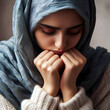 A young Muslim girl with a headscarf and bowed head. Her defensive posture expresses concern, loneliness, sadness. Concept of a woman with a broken heart.