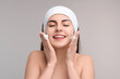 © New Africa - Young woman with headband washing her face on light grey background