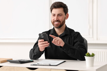 Poster - Smiling man using smartphone at table in office