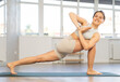 © JackF - Young attractive smiling woman practicing yoga, doing revolved side angle pose in modern yoga gym