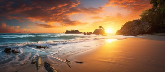 Wall Mural - The sun setting on a beautiful beach with waves crashing against a rugged rocky cliff in the background