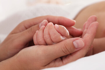 Canvas Print - Mother with her cute baby on bed at home, closeup of hands