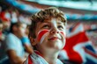 A young boy with red, white and blue face paint is smiling at the camera. Fan at the European Football Championship