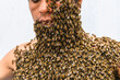 Close-up of a person draped in swarming honeybees, showcasing the bond between humans and insects