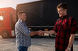 Truck driver and fleet manger , shaking hands after successful day, beautiful sunset 