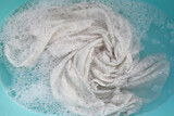Fototapeta Sypialnia - Women's lace dress soaked in water dissolved detergent with white foam bubble. Laundry concept