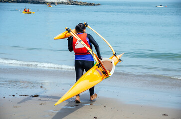 Kayaker carrying kayak towards sea