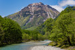 River Azusa flowing through the highland Kamikochi valley with towering, snow-capped mountains behind