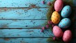   A collection of blue-painted Easter eggs atop a wooden table, adjacent to a bunch of pink blooms