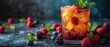   A glass of ice tea, garnished with raspberries and blueberries, sits on a table Mint leaves gracefully rest among the fruits