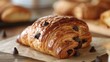 Fresh chocolate croissant on wooden surface. Close-up food photography.