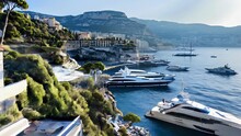 Yachts Of Various Sizes Docked In A Luxurious Marina In Monaco, Set Against The Mediterranean Sea. Sheer Cliffs Rise Up Behind, Topped With Gleaming White High-end Residences. 