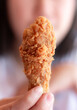 Woman eating fried chicken blurred background