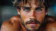 Close-up portrait of a young man with striking blue eyes and stubble, exuding a rugged charm.