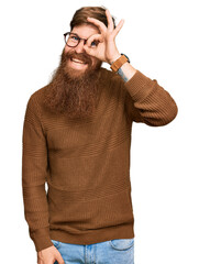 Wall Mural - Young irish redhead man wearing casual clothes and glasses doing ok gesture with hand smiling, eye looking through fingers with happy face.