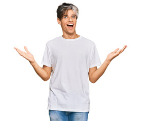 Wall Mural - Young hispanic man wearing casual white tshirt celebrating victory with happy smile and winner expression with raised hands