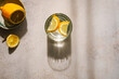 Ein Glas mit Wasser und Zitronen auf einem grauen Tisch. Schlagschatten, kontrastreich, Draufsicht.