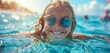 Happy smiling girl child in sunglasses swims in the sea. Summer sunny day. Front view from low angle.