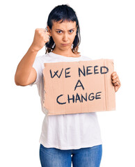 Sticker - Young woman holding we need a change banner annoyed and frustrated shouting with anger, yelling crazy with anger and hand raised