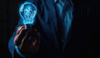 A hand holds a glowing light bulb symbolizing innovation and creative thinking for business concepts against a black background. A businessman in a suit holds his hand out to a digital virtual icon