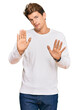 Handsome caucasian man wearing casual white sweater moving away hands palms showing refusal and denial with afraid and disgusting expression. stop and forbidden.